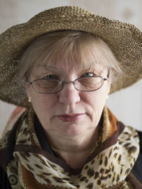 Portrait of senior woman wearing hat sitting against wall at home