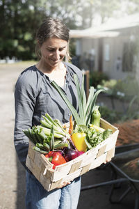 Happy woman carrying vegetables in basket