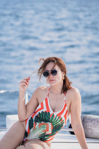 Young woman wearing sunglasses while swimming in sea