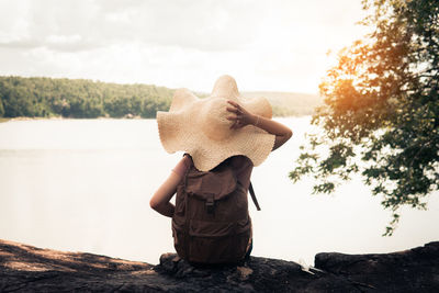 Rear view of woman standing on rock against sky