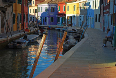 Boats moored in canal amidst buildings in city