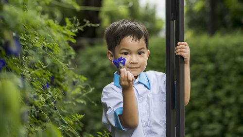 Portrait of boy standing against plants