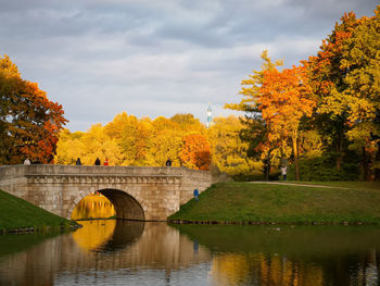 Arch bridge over river against sky during autumn