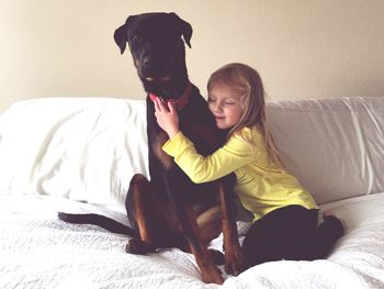 Close-up of girl embracing dog on bed at home