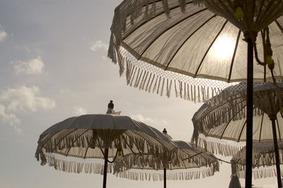 Beautiful white balinese sun umbrella during sunset, decorated with yellow bulb lights