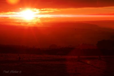 Scenic view of dramatic sky over landscape during sunset