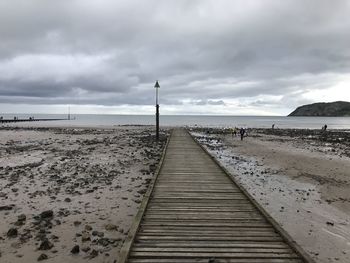 Pier on beach against sky