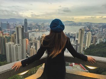 Rear view of woman standing by railing against cityscape