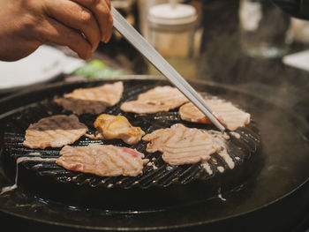 Close-up of person preparing food in cooking pan