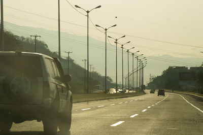 Cars on street in city against sky