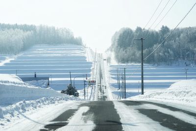 Snow covered road by mountain against clear sky