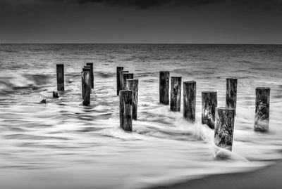 Wooden posts on beach against sky