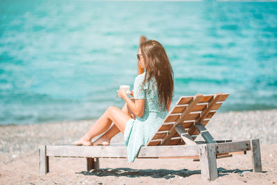 Woman sitting on bench in sea