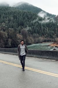 Smiling man walking on road against trees