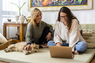 Woman using phone while sitting on laptop