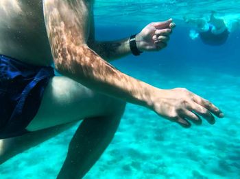 Low section of man swimming in sea