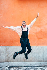 Full length of woman jumping against wall