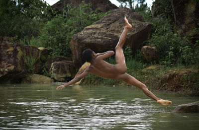 Full length of naked boy jumping in lake