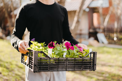 Rear view of man holding flowering plant