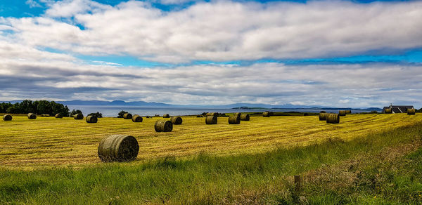 Hay bales on field against sky