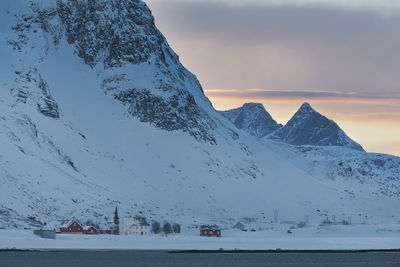 Scenic view of sea by snowcapped mountains against sky