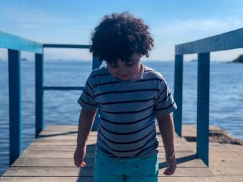 Boy standing on pier over sea