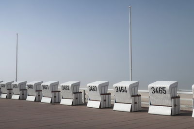 Hooded beach chairs on promenade against clear sky