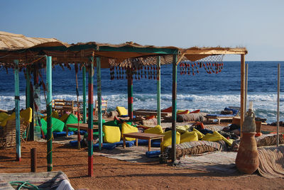 People sitting on chair at beach against clear sky