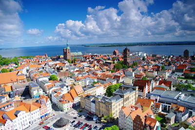 High angle view of town by sea against sky
