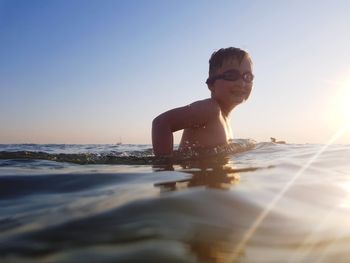 Portrait of boy in sea against clear sky