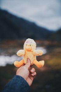 Close-up of hand holding toy against sky