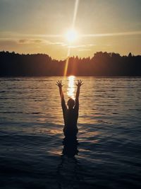 Silhouette person at shore against sky during sunset