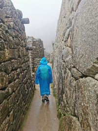 Rear view of man walking against wall