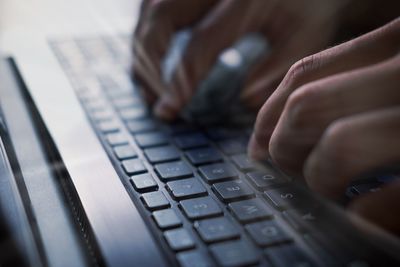 Cropped image of hand typing on keyboard