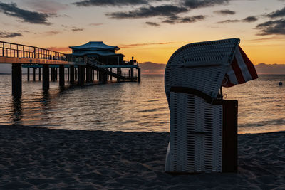 Wooden posts on beach against sky during sunset