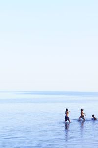 People on sea against clear sky