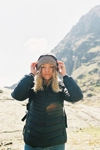 Portrait of backpacker standing on snow covered landscape against sky