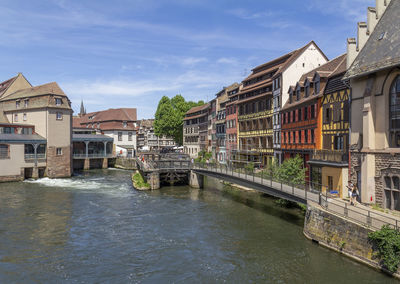 Bridge over river by buildings against sky