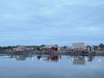 Buildings by lake against sky