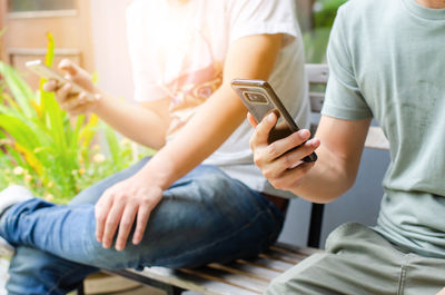 Midsection of men using mobile phone while sitting on bench