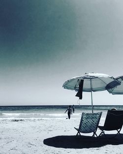 Chairs on beach against clear sky