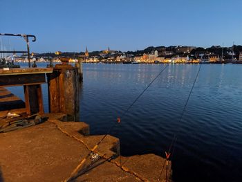 Scenic view of sea by buildings in city against clear sky