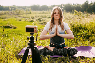 The girl practices yoga in nature and records a video lesson about yoga. yoga online