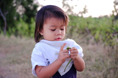 Girl eating green pea while standing on land