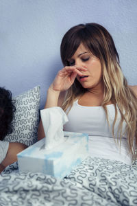 Young woman suffering from cold on bed at home