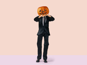 Low angle view of person standing by pumpkin against orange background