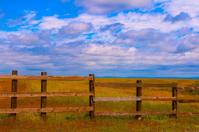 Wooden fence on field against sky