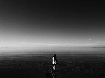 Full length of woman standing in sea against sky