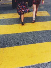 Low section of women walking on zebra crossing