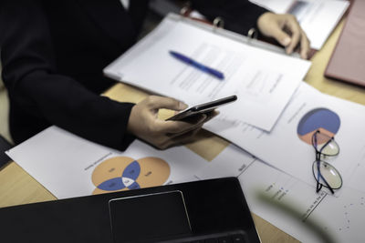 Midsection of man using mobile phone on table